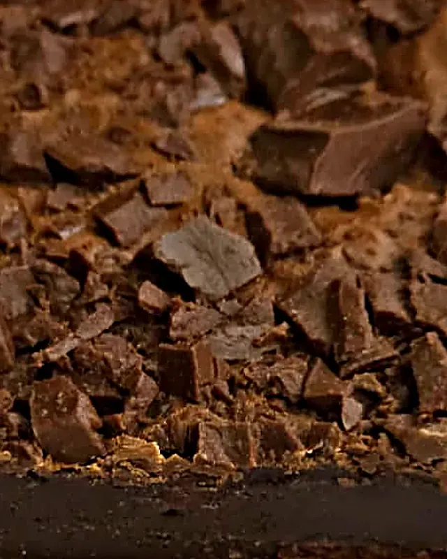 Fatia de brownie de lado, mostrando a base escura e o miolo cremoso